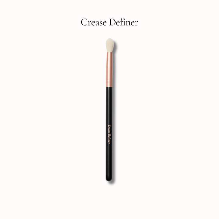 Makeup brush labeled 'Crease Definer' on a white background